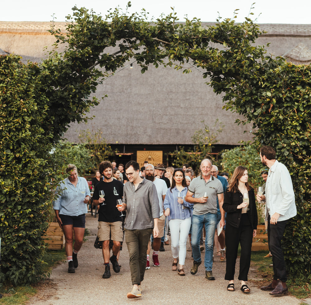 A group of barn visitors attending a wine tour, walking out of the venue and holding empty wine glasses
